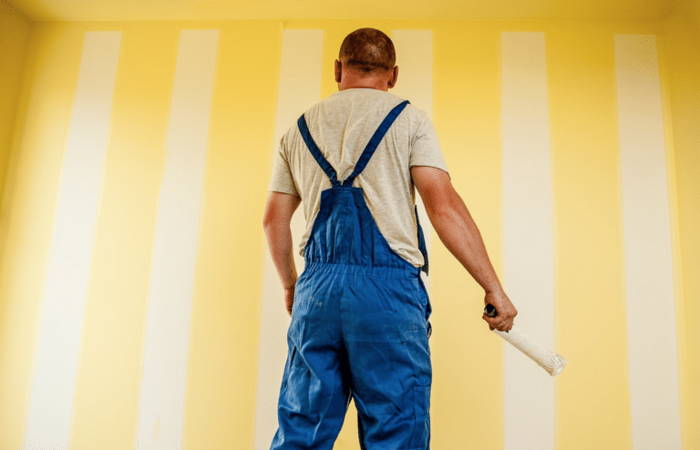 Ein Handwerker streicht einen Raum mit gelben Streifen.