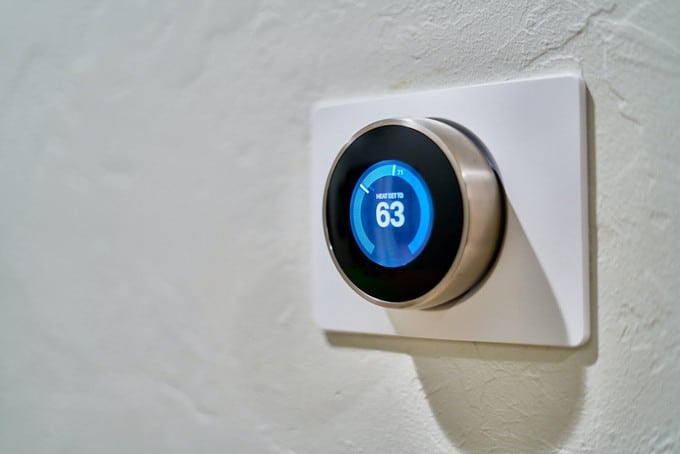 An einer Wand ist ein intelligenter Thermostat angebracht.