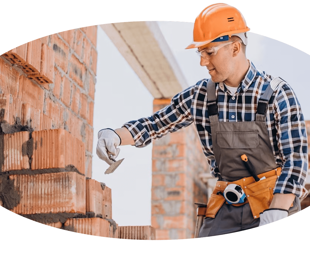 Ein Bauarbeiter bedient einen Kran, während er an einer Ziegelwand arbeitet.