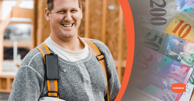 Ein Mann mit Schutzhelm lächelt vor einem Stapel Geld.