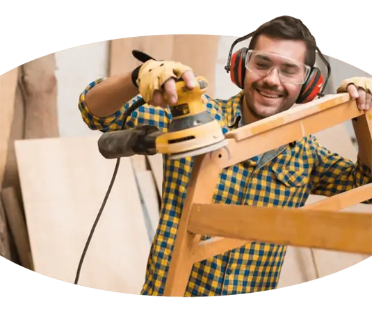 Ein Mann mit Kopfhörern schleift Holz mit einer Schleifmaschine.